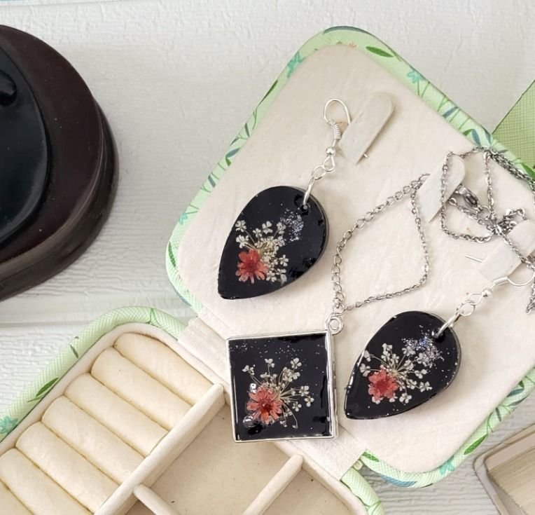 The square pendant and both teardrop earrings on their silver hooks, arranged on a mint-and-cream jewellery case, the chains looped loosely around them