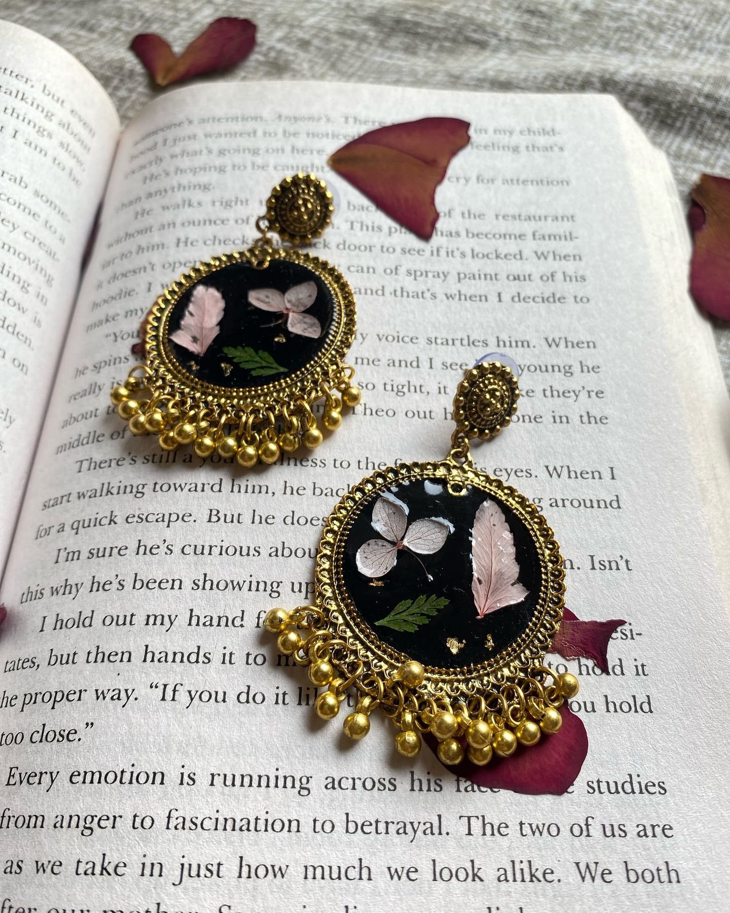 The pair of jhumkas seen straight on against the book, showing the full bead fringe