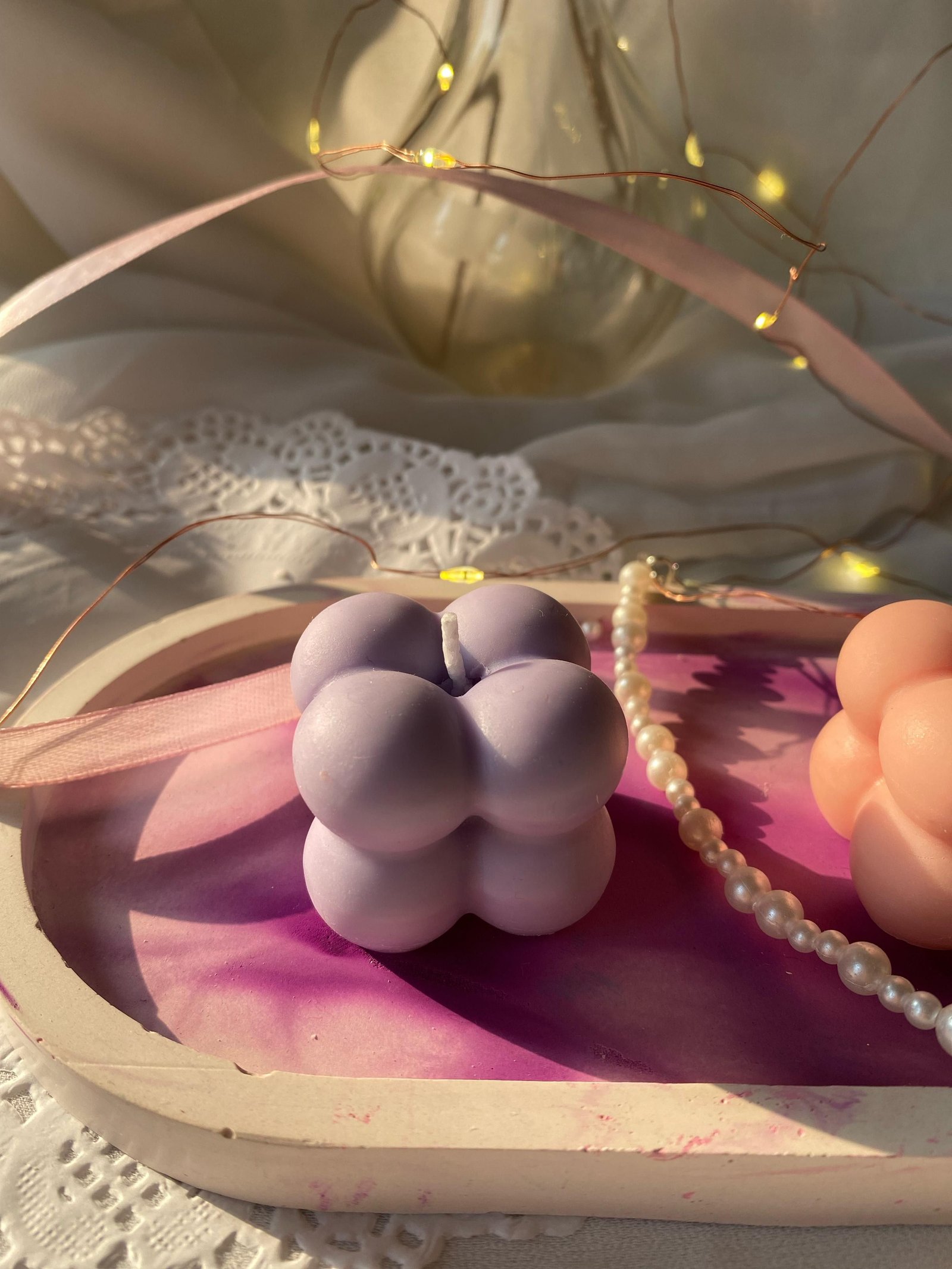 A lilac bubble candle on the same dish, lit by fairy lights