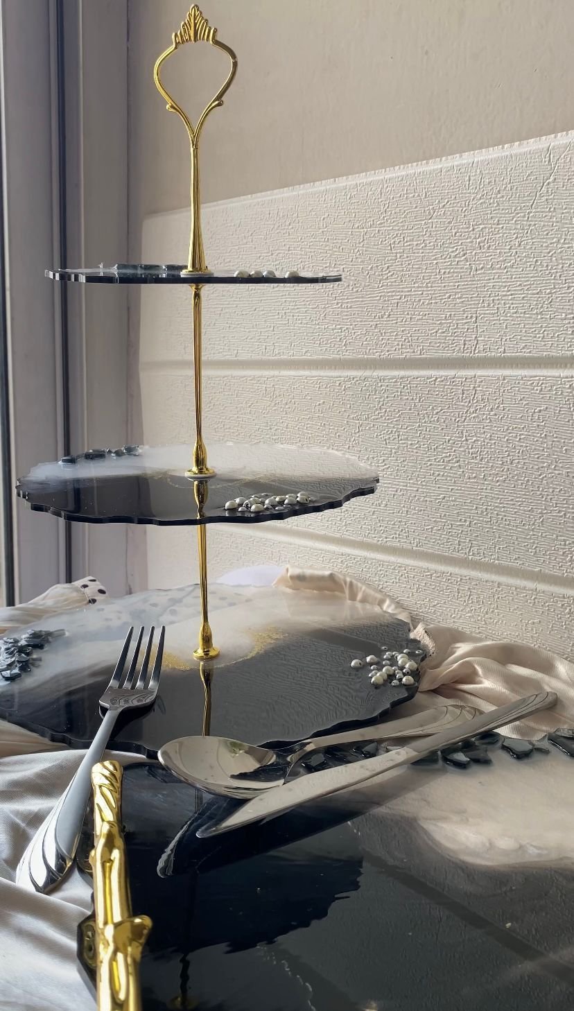 The whole stand photographed against a plain wall, standing on a matching marbled platter with gold-handled cutlery beside it