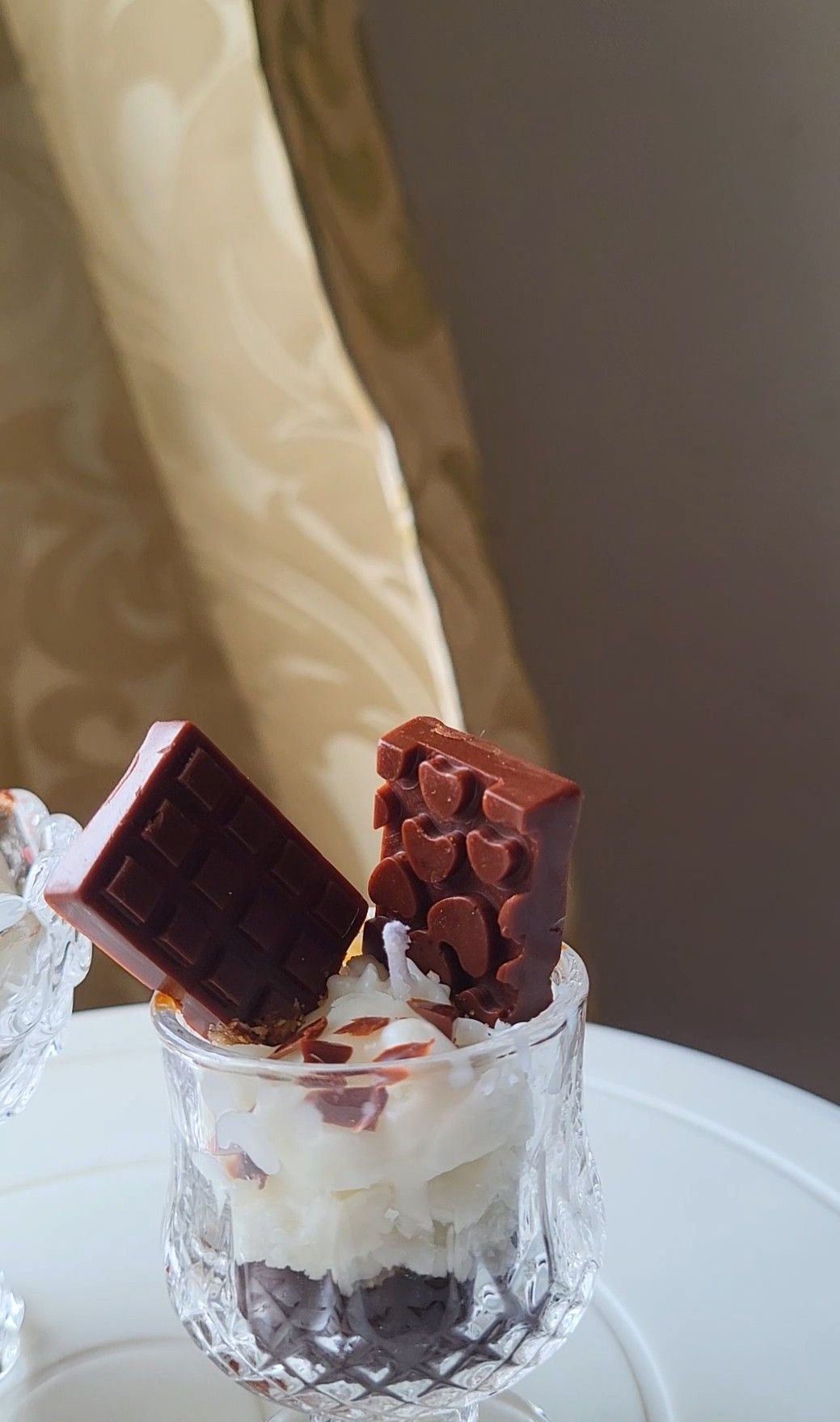 A second dessert candle in a tumbler, with chocolate pieces standing upright in the cream