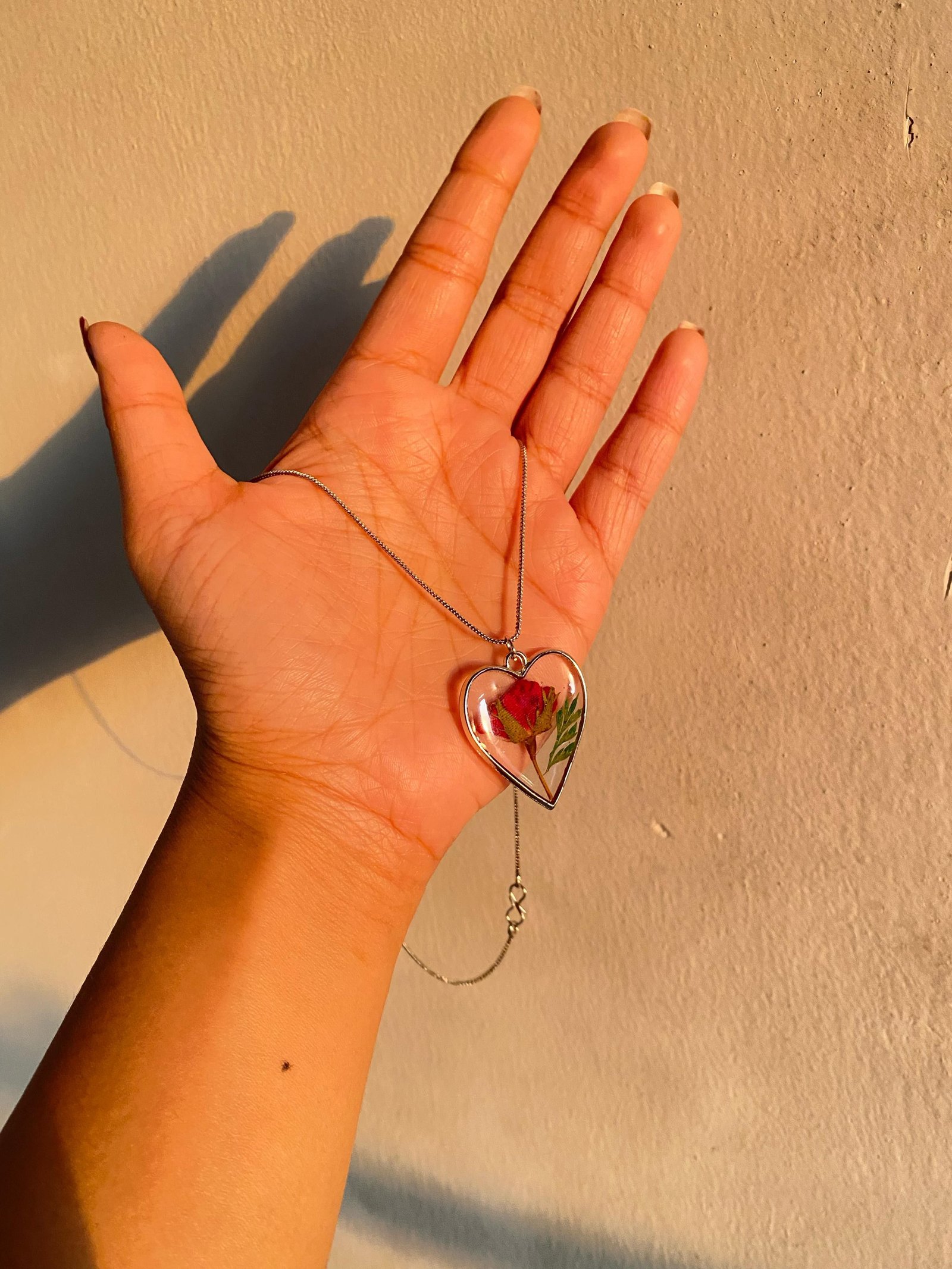 The heart pendant held flat in the palm of a hand