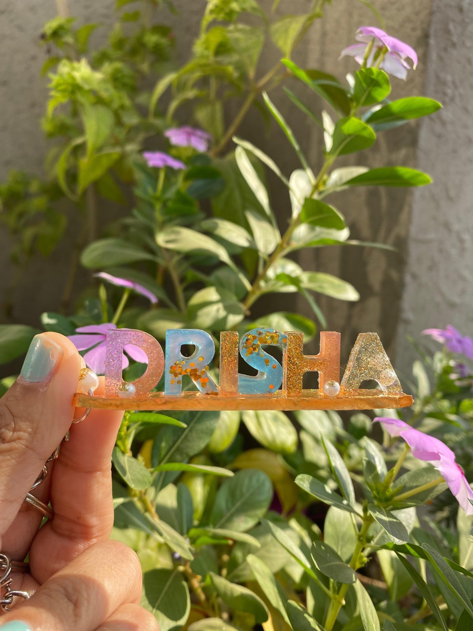 A personalised resin keychain spelling a name in pastel letters set with gold leaf