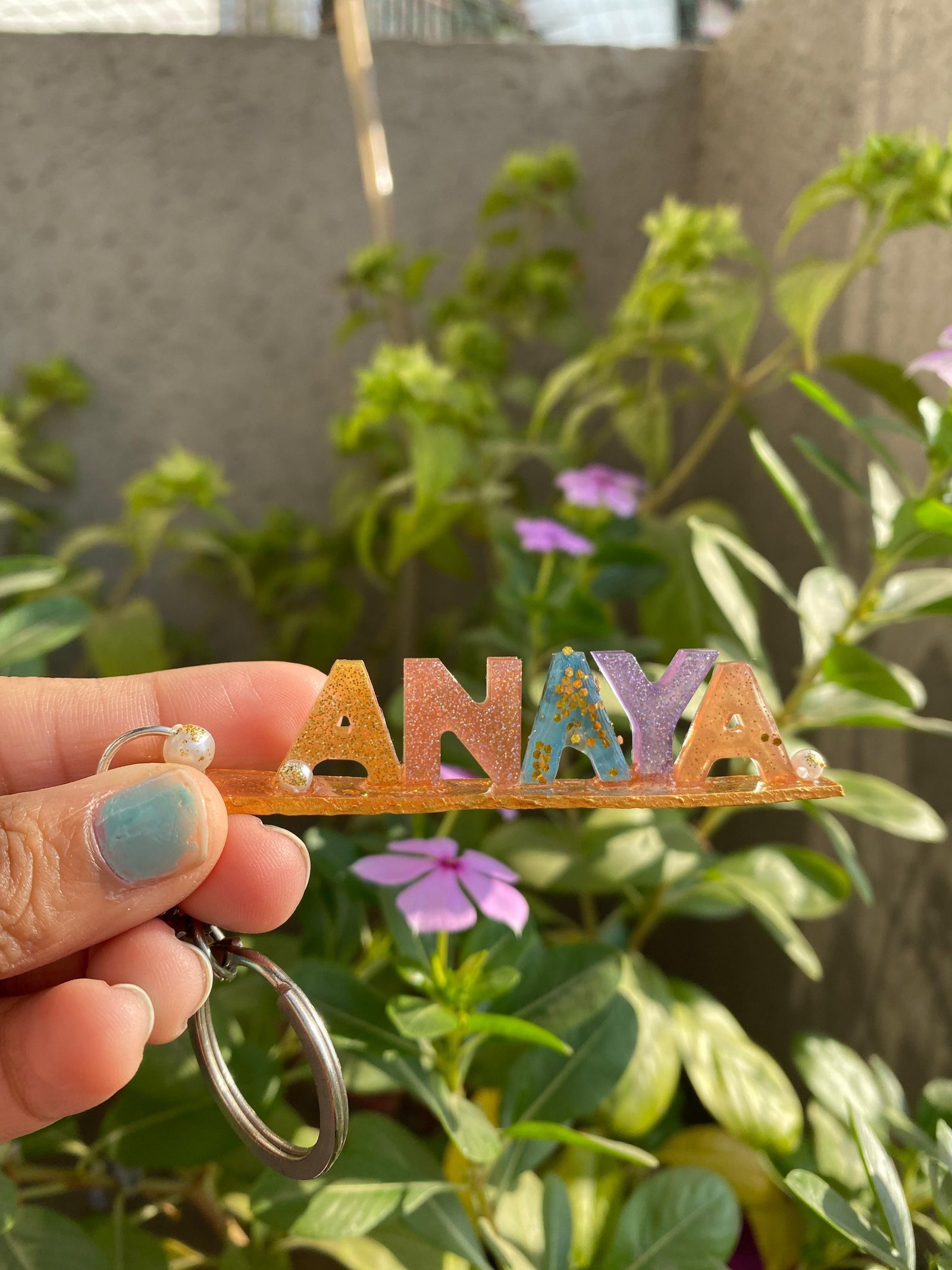 A second name keychain, in blue and gold, held in the hand
