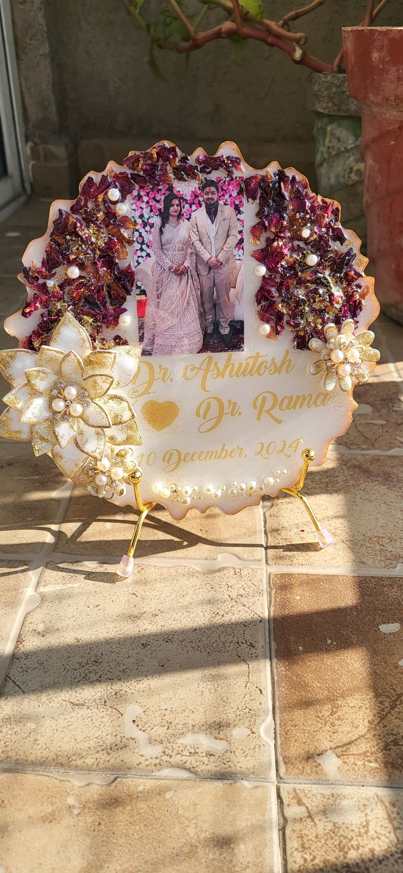 A personalised resin plaque holding a couple’s names, their wedding date and a photograph, framed by preserved flowers and pearls