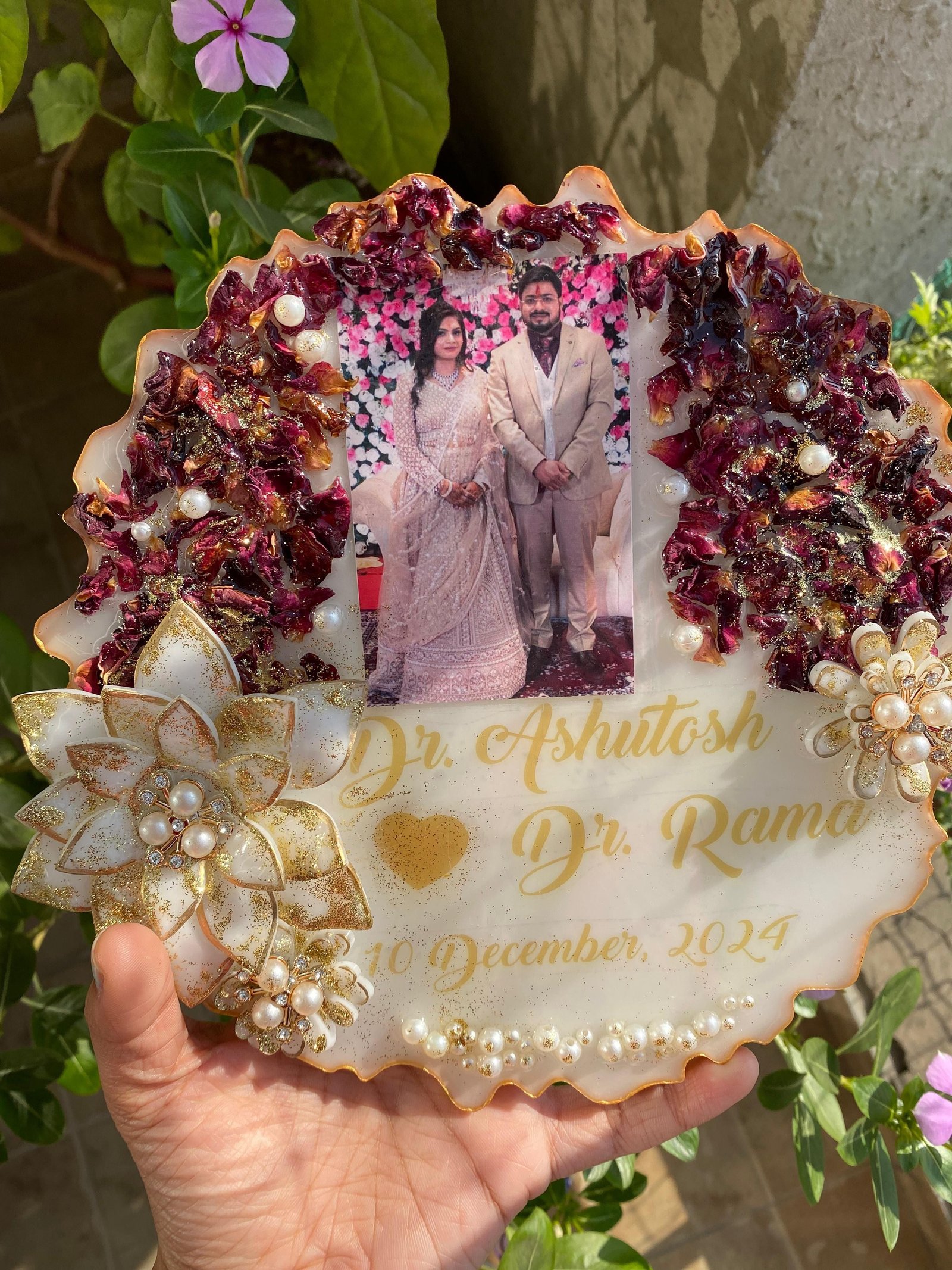 The same plaque held in the hand, showing the preserved petals set around its edge