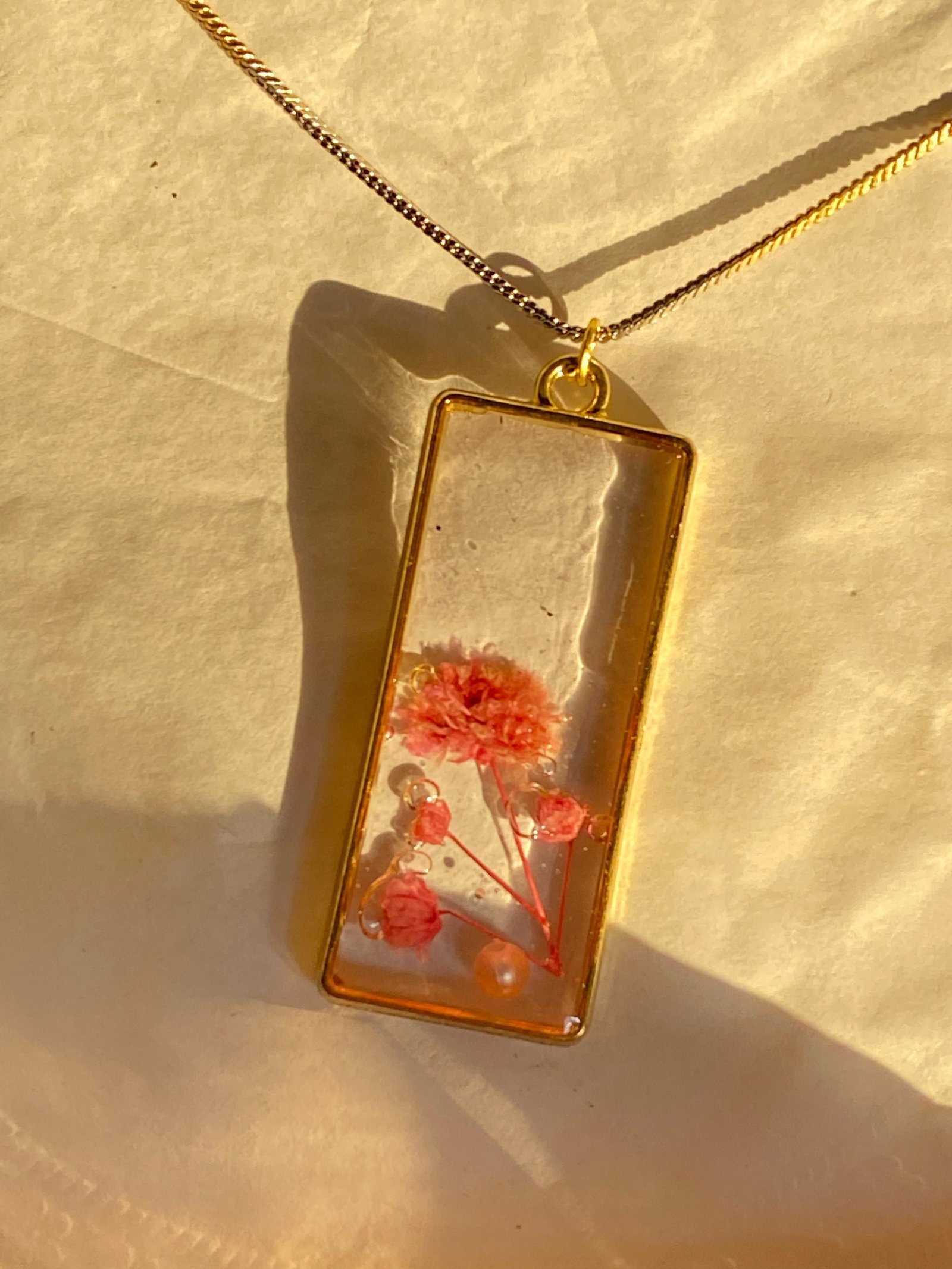 The same pendant lit from the side, showing the flowers through the resin