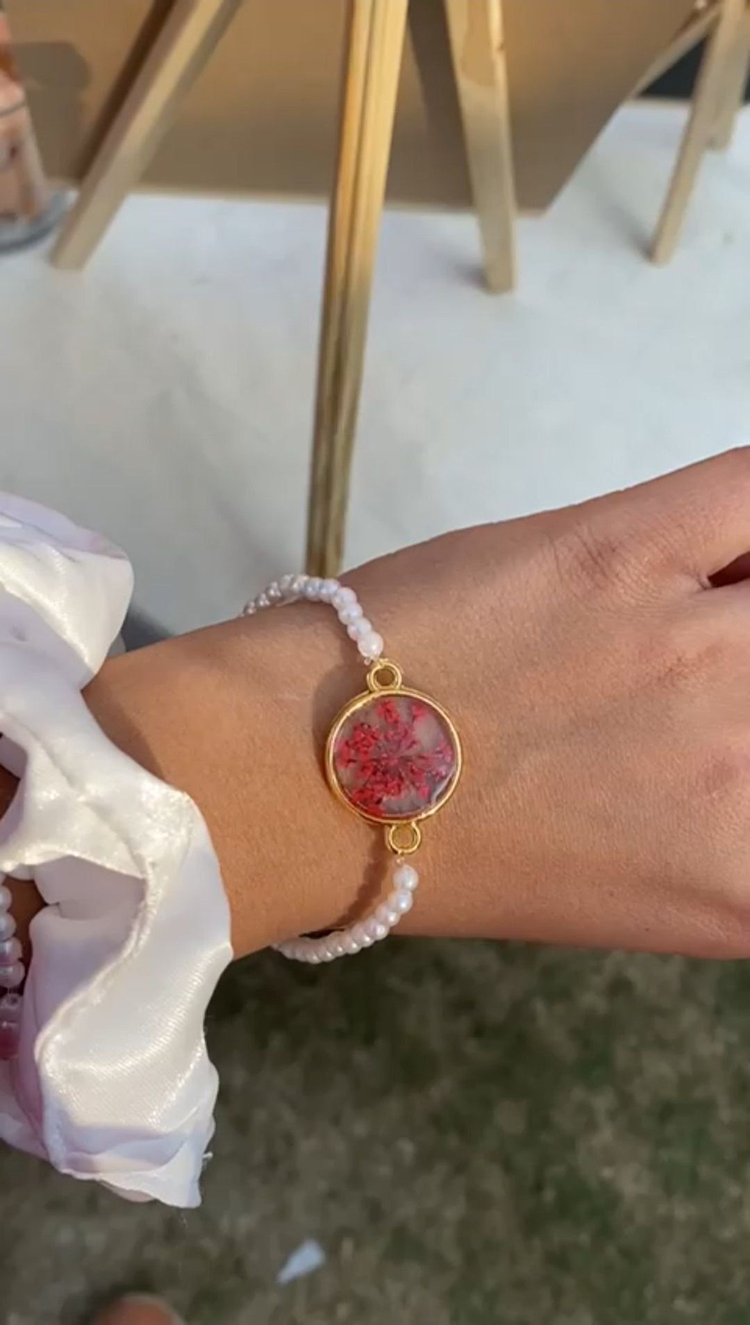 A gold-set bracelet on a pale beaded band, worn with a scrunchie in daylight