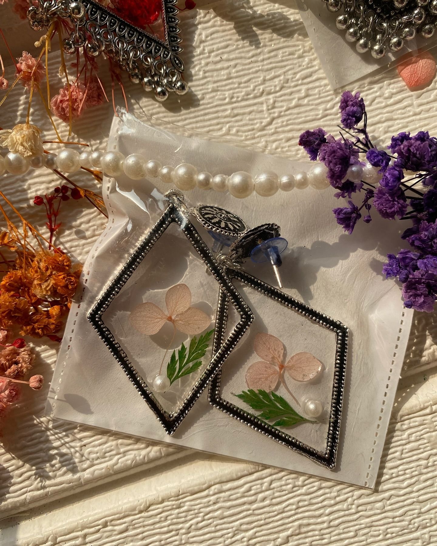 A pair of resin jhumkas set with a pressed flower