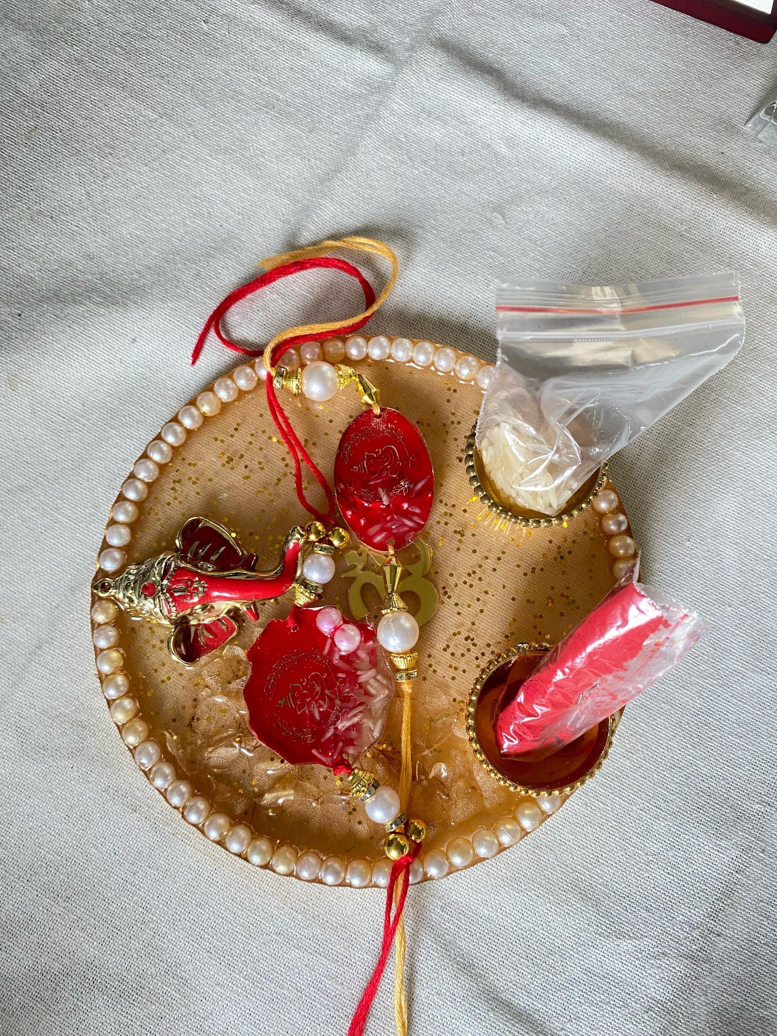 A smaller round tray in cream and gold set with red flowers and pearls