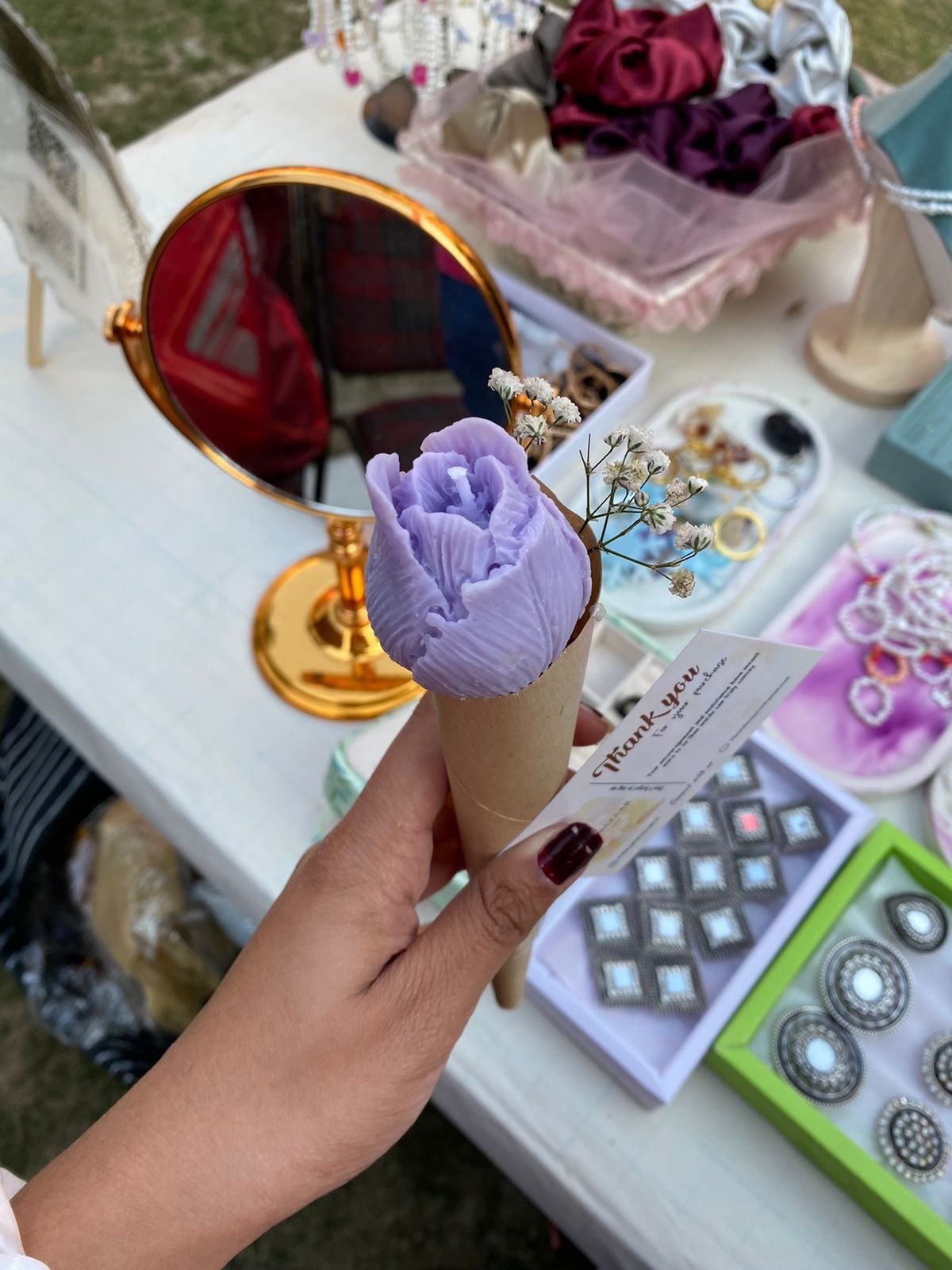 A lilac rose in a cone, held up in the sunlight
