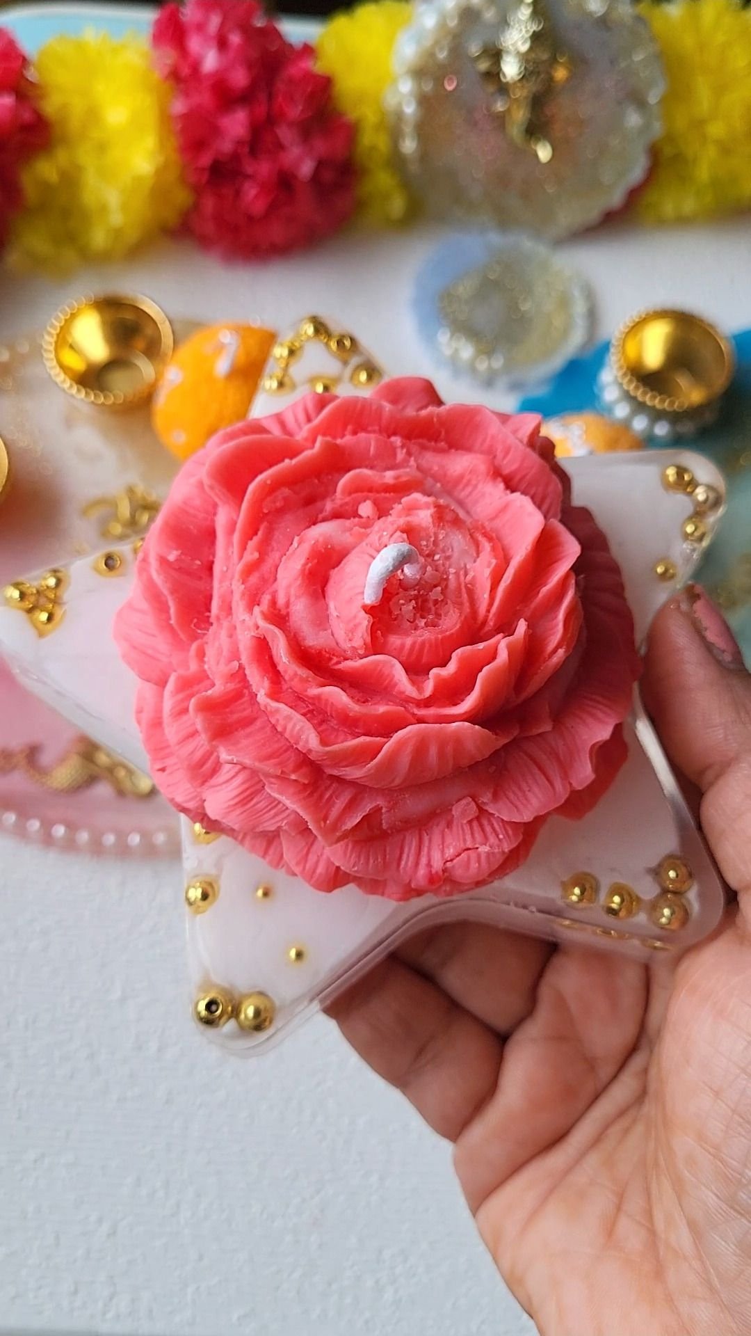 A coral rose candle set on a pearl-edged tray