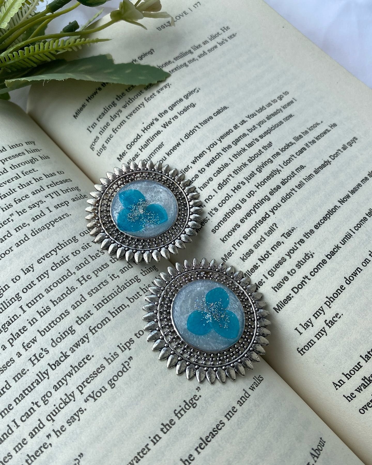 The earrings with the gold chains drawn across the book