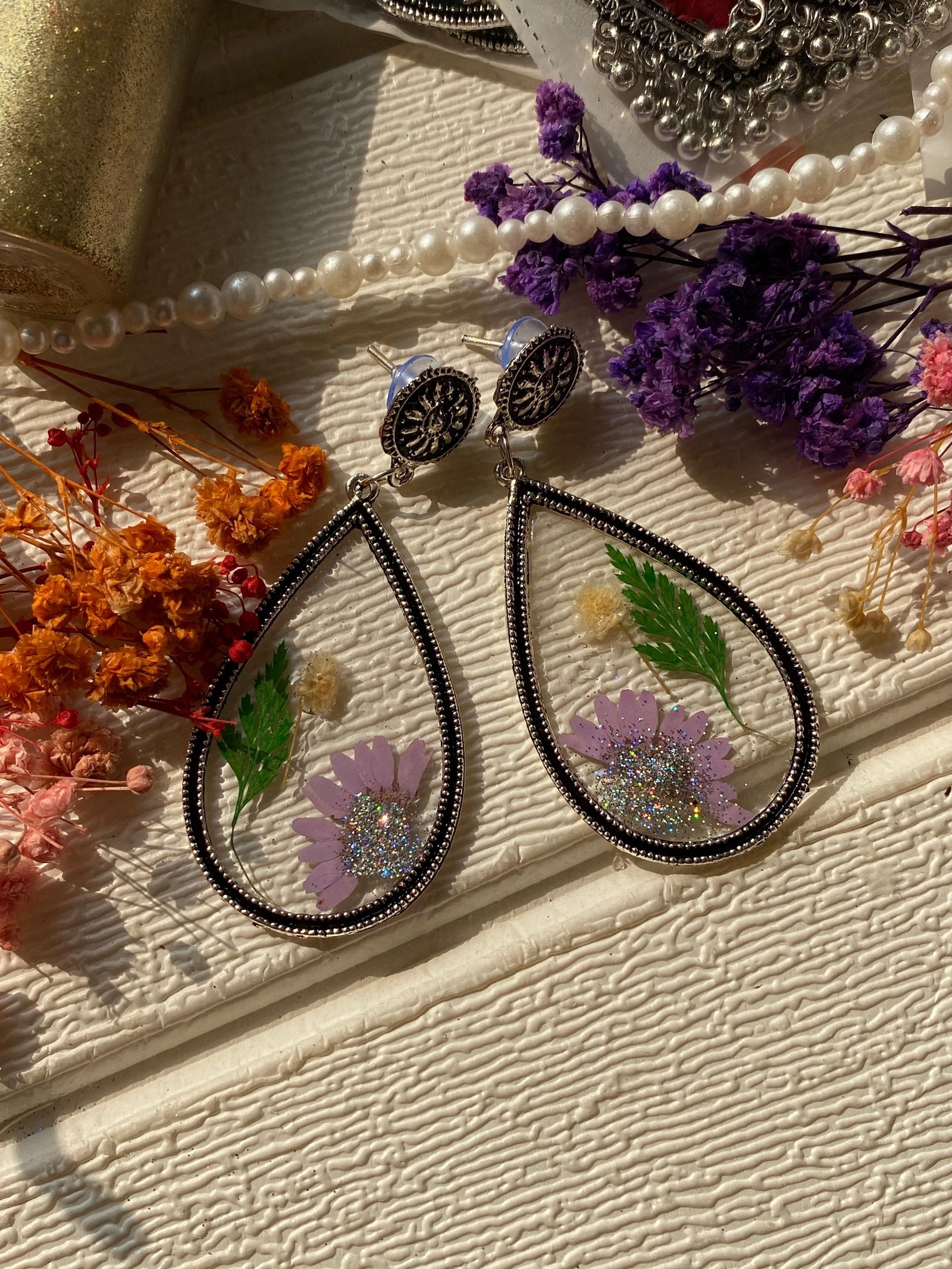 The same shape made with lilac and white flowers, photographed beside pearls and dried blooms