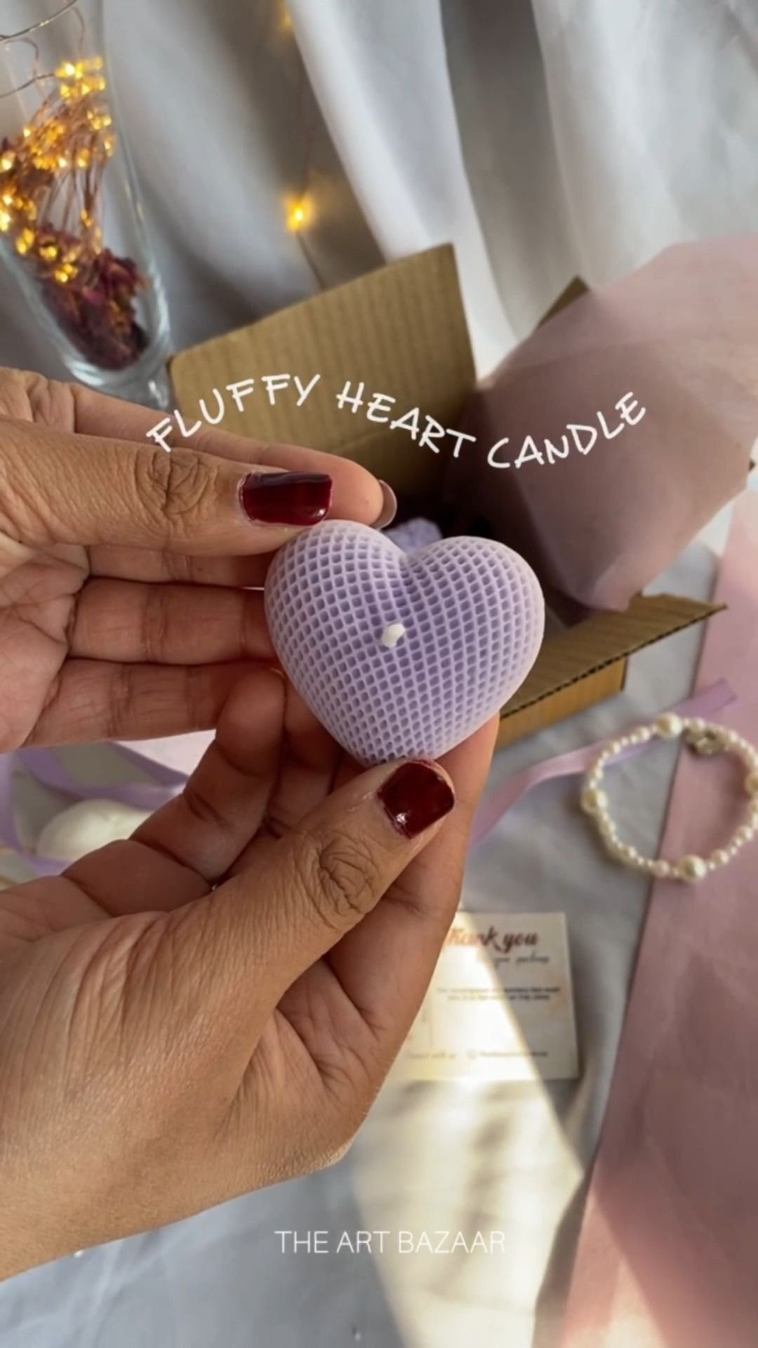 A quilted heart candle held between two fingers