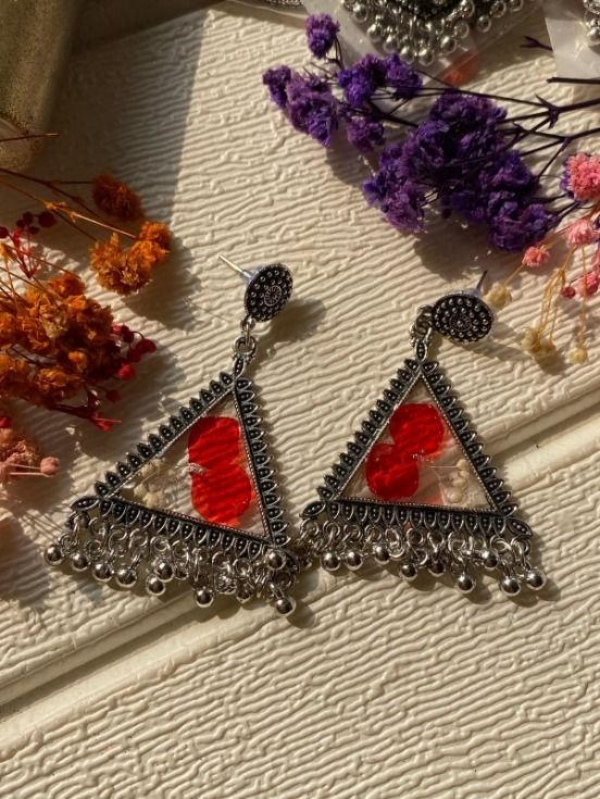 The same triangular frames in a red version, each with a red bloom and a small cream flower set in the resin, laid on the same cream ground